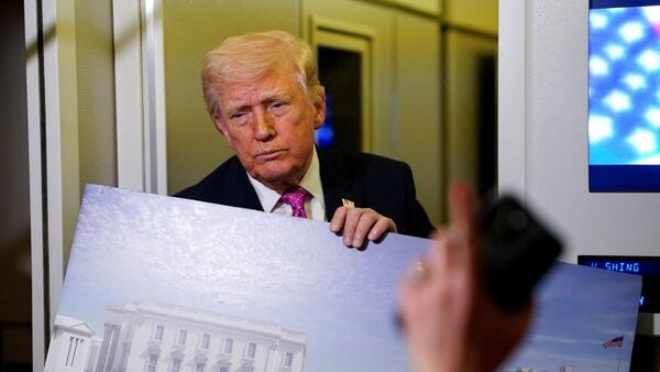 A member of the media raises her hand for a question as US President Donald Trump talks while holding up renderings of the planned White House ballroom, aboard Air Force One en route to Joint Base Andrews, Maryland (Image: Reuters)