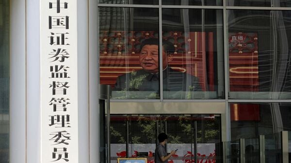 FILE PHOTO: A man stands near a screen showing news footage of Chinese President Xi Jinping at the China Securities Regulatory Commission (CSRC) building on the Financial Street in Beijing, China July 9, 2021. REUTERS/Tingshu Wang/File Photo