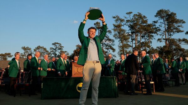 Golf - The Masters - Augusta National Golf Club, Augusta, Georgia, U.S. - April 12, 2026 Northern Ireland's Rory McIlroy celebrates with his green jacket and the trophy after winning The Masters REUTERS/Brian Snyder
