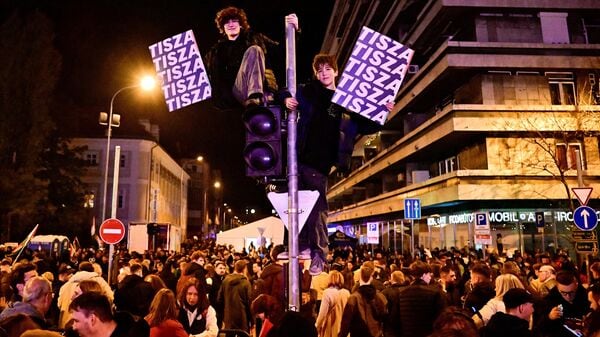 People hold signs with the name of the opposition Tisza party as others gather after the announcement of partial results of the parliamentary election, in Budapest, Hungary, April 12, 2026. REUTERS/Marton Monus     TPX IMAGES OF THE DAY