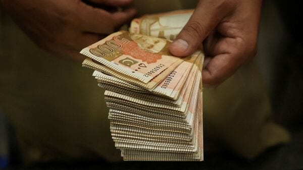 Pakistan economy: A trader counts Pakistani rupee notes at a currency exchange booth in Peshawar, Pakistan, July 29, 2025.