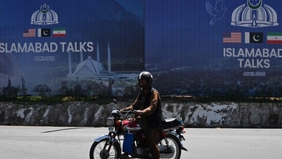 A commuter rides past a billboard for the US-Iran peace talks in Islamabad on April 13, 2026, a day after Iran and the United States failed to reach an agreement to end the war in West Asia. (AFP File)