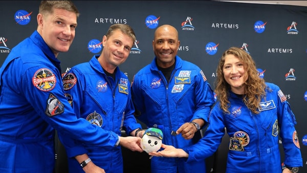 The Artemis II crew pose with the zero gravity indicator named Rise that also holds a SD card containing the names of millions who will fly with the crew around the Moon. “Rise” was inspired by the iconic Earthrise moment from the Apollo 8 mission.