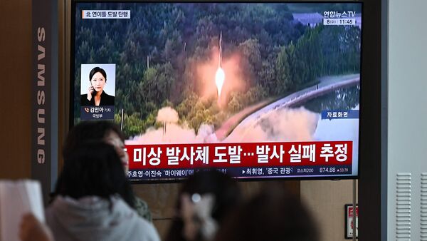 People watch a television screen showing a news broadcast with file footage of a North Korean missile test, at a train station in Seoul on 8 April 2026.