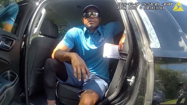 In this image from police body camera video released by the Martin County, Fla., Sheriff's Office, golfer Tiger Woods sits in an unmarked police vehicle as he speaks with law enforcement personnel following a car crash in Jupiter Island, Fla., Friday, March 27, 2026. (Martin County Sheriff's Office via AP)