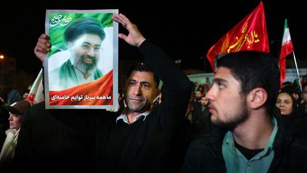 US Iran War LIVE: TOPSHOT - An Iranian man holds up picture of Iranian supreme leader Ayatollah Mojataba Khamenei as others react to a ceasefire announcement at the Enqelab square, in Tehran, on April 8 2026. The United States and Iran agreed to a two-week ceasefire Tuesday barely an hour before US President Donald Trump's deadline to obliterate the rival country was set to expire, with Tehran to temporarily reopen the vital Strait of Hormuz. (Photo by AFP) /