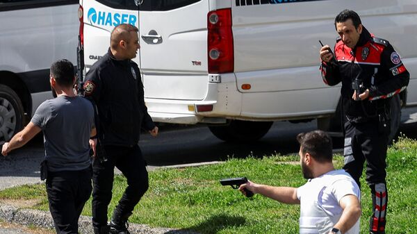 A plainclothes police officer holds a gun, after gunfire was heard near the building housing the Israeli consulate, according to a witness, in Istanbul, Turkey, April 7, 2026. REUTERS/Murad Sezer