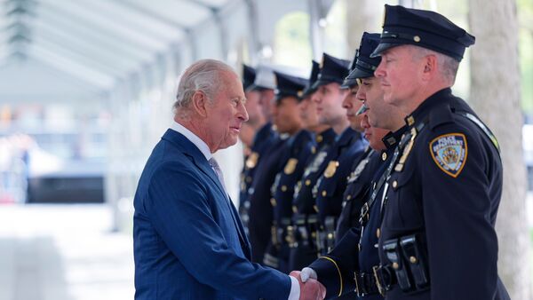 Britain's King Charles III shakes hands with a police officer as he and Queen Camilla visit the 9/11 Memorial, Wednesday, April 29, 2026, in New York.