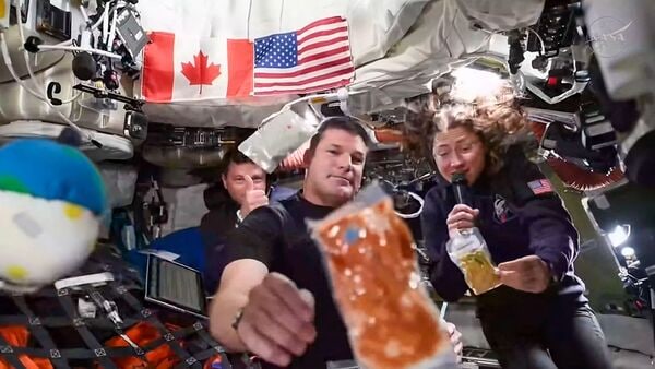 This screengrab taken from a NASA livestream shows Artemis II mission astronauts (L-R) NASA's commander Reid Wiseman, Canadian Space Agency's mission specialist Jeremy Hansen and NASA's mission specialist Christina Koch during a brief demonstration of the food they eat in space to respond a question during a VIP call with Canadian children inside the Orion spacecraft while on their way to the Moon on April 4, 2026. (Photo by Handout / NASA / AFP)