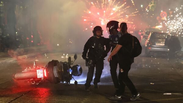 Police try to disperses PSG supporters who left off fireworks as they celebrate in Paris, Saturday.