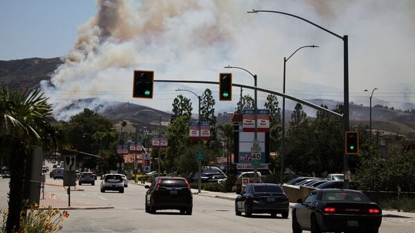 Vehicles drive as smoke from the wildfire known as the Sandy Fire billows, in Simi Valley, California, U.S., May 18, 2026. REUTERS/Daniel Cole