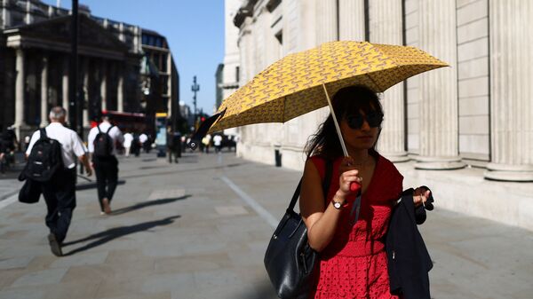 A woman shields herself from the sun with an umbrella during a heatwave in London, Britain.