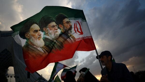 A man holds a flag with a picture of late leader of the Islamic Revolution Ayatollah Ruhollah Khomeini, late Supreme Leader of Iran Ayatollah Ali Khamenei and Iran's new Supreme Leader Mojtaba Khamenei, during a rally in Tehran, Iran, April 29, 2026.