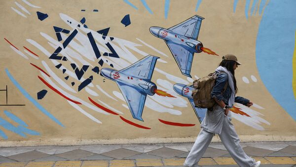 An Iranian woman walks next to an anti-Israeli mural on a street in Tehran