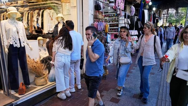 People walk along a sidewalk in northern Tehran, Iran, Sunday, May 10, 2026