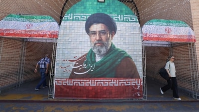 Iranian commuters walks past a large tiled image of Iran's current leader Ayatollah Mojtaba Khamenei, at the entrance to the metro in Tehran. (AFP)