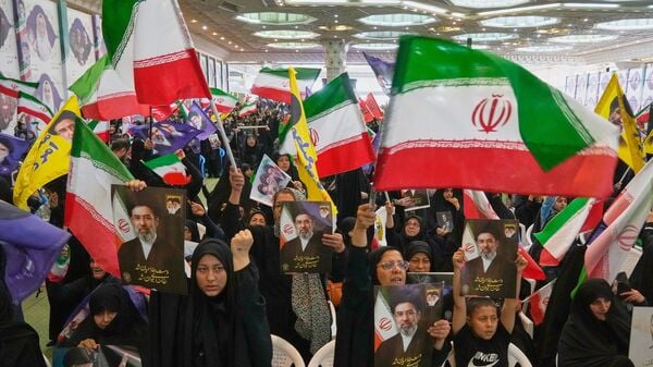 Government supporters hold Iranian flags and pictures of Iran's Supreme Leader, Ayatollah Mojtaba Khamenei, during a ceremony honoring the armed forces and those killed in the war with Israel and the U.S. at the Imam Khomeini Grand Mosque in Tehran, Iran, Sunday, May 24, 2026. (AP Photo/Vahid Salemi)