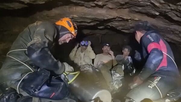 This screengrab made from handout video footage taken on May 29, 2026, and provided by Benz Norrased Palasing of Seascout Diving, shows a rescue team (foreground) training people (background) trapped in a semi-submerged cave how to use diving equipment before the first of them was freed, in central Xaysomboun province, northeast of the capital Vientiane. A rescue team freed on May 29, one of seven men trapped inside a semi-submerged cave in Laos for more than a week, the group working at the site said.
