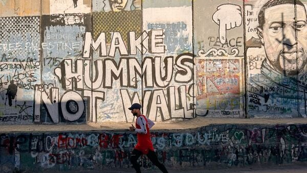 Palestinian Mohamad Al-Assi, who was released from Israeli detention six months ago, runs past Israel's separation wall as he trains ahead of the Palestine Marathon in the West Bank city of Bethlehem, Thursday, May 7, 2026. (AP Photo/Sam Metz)