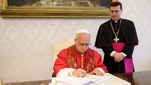 TOPSHOT - This photo taken on May 15, 2026 and handout on May 25, 2025 by The Vatican Media shows Pope Leo XIV signing his first Encyclical Letter 'Magnifica Humanitas', focused on the rise of artificial intelligence,  in The Vatican.