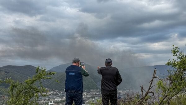 Local residents observe smoke rising above buildings following a recent drone attack on the Tuapse oil refinery in Tuapse, Krasnodar region on April 29, 2026.