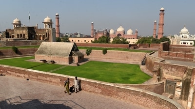 People walk on the premises of Lahore Fort with the historic Badshahi Mosque in the background, in Lahore. (Murtaza Ali/Reuters Photo)