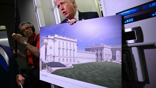 A file image of US President Donald Trump holding a rendering of the East Wing modernization as he speaks to reporters aboard Air Force One en route to Joint Base Andrews, Maryland