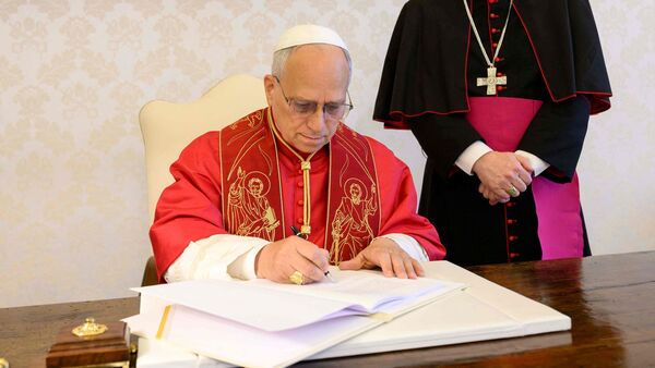 This photo taken on May 15, 2026 and handout on May 25, 2025 by The Vatican Media shows Pope Leo XIV signing his first Encyclical Letter Magnifica Humanitas, focused on the rise of artificial intelligence, in The Vatican. (Photo by Handout / VATICAN MEDIA / AFP)