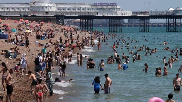 People enjoy the weather in the sea and on in the beach in Brighton, on the south coast of England on June 25, 2026, during a heatwave.  (Photo by CARLOS JASSO / AFP)