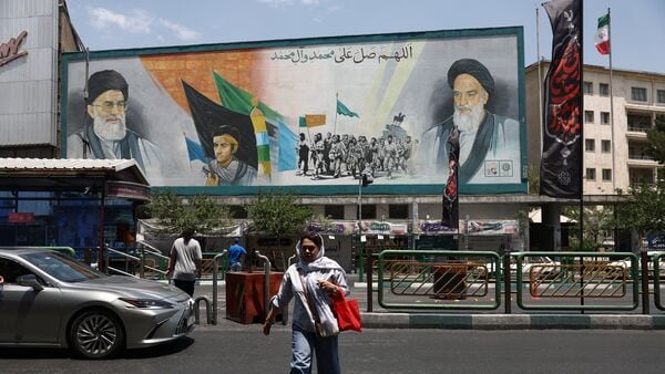 A woman walks near a mural depicting the late leader of the Islamic Revolution, Ayatollah Ruhollah Khomeini, and Iran's late Supreme Leader Ayatollah Ali Khamenei, on a street in Tehran, Iran, June 18, 2026.