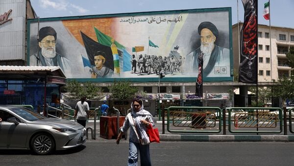 A woman walks near a mural depicting the late leader of the Islamic Revolution, Ayatollah Ruhollah Khomeini, and Iran's late Supreme Leader Ayatollah Ali Khamenei, on a street in Tehran, Iran, June 18, 2026. Majid Asgaripour/WANA (West Asia News Agency) via REUTERS