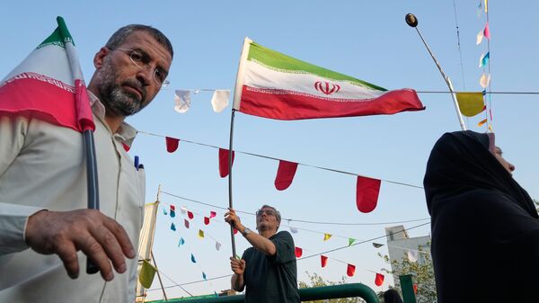 A man waves an Iranian flag during a street festival celebrating the Muslim Shiite holiday of Eid al-Ghadir, the anniversary Prophet Muhammad naming his successor, Ali, who is revered as the first Shiite Imam, in Tehran, Iran, Thursday, June 4, 2026.