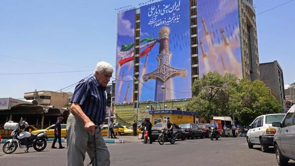 Iran US War News LIVE Updates: A man walks past a giant banner depicting Iranian missiles and a sword belonging to Imam Ali, the first Imam of the Shiites, at the Vanak Square in Tehran