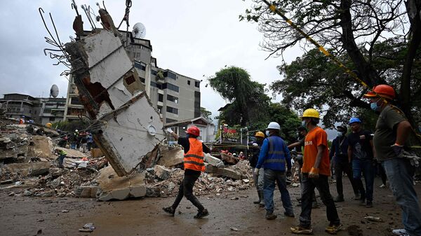 Workers remove debris from a collapsed building in the San Bernardino neighborhood of Caracas on June 28, 2026, following earthquakes. (Photo by Federico PARRA / AFP)