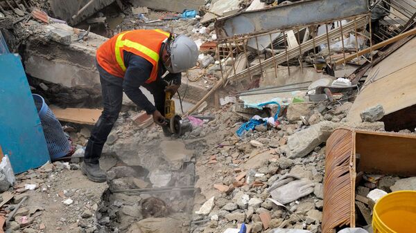 A rescuer uses a grinder while trying to retrieve a body in Caraballeda, La Guaira State, Venezuela on June 28, 2026.