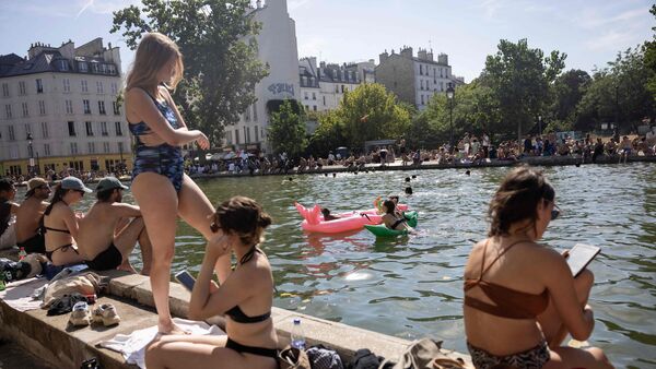 People sit by the Canal Saint-Martin as France experiences a heatwave in Paris