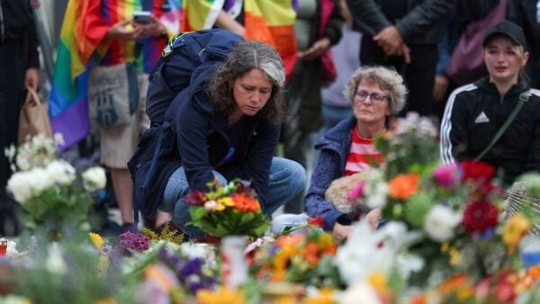People gather around flowers, mementos and candles left at the Brandenburg Gate, after a deadly incident in which a vehicle crashed into a crowd near Berlin's annual Christopher Street Day Pride parade on Saturday evening, leaving multiple people injured and the parade called off, in Berlin, Germany, July 26, 2026.  REUTERS/Maryam Majd
