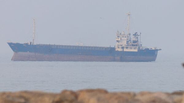 A man walks on a road while vessels are in the Strait of Hormuz near the beach of Bandar Abbas, Iran, June 30, 2026.