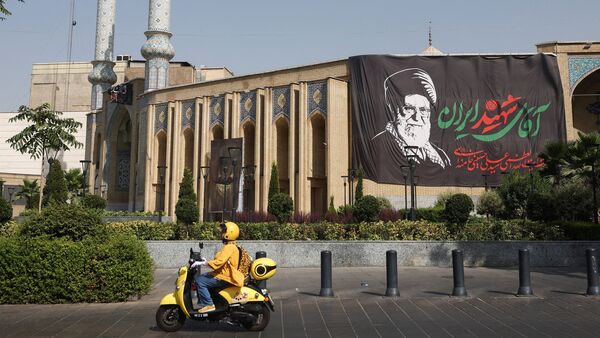 An Iranian woman rides a motorcycle next to a banner with a picture of the late Supreme Leader of Iran, Ayatollah Ali Khamenei, on a street in Tehran, Iran, July 12, 2026. Majid Asgaripour/WANA (West Asia News Agency) via REUTERS