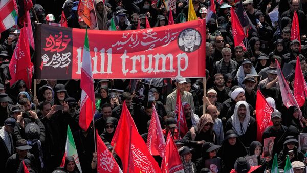 Two mourners carry a banner reading: 'kill Trump' as an other one waves an anti-U.S. banner during the funeral procession of the late Iranian Supreme Leader Ayatollah Ali Khamenei in Tehran, Iran, Monday, July 6, 2026. (AP Photo/Vahid Salemi)