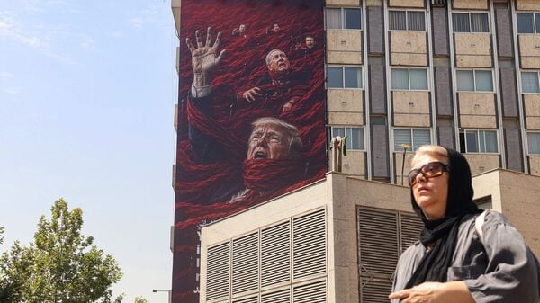 An Iranian woman walks in front of a huge anti-US and Israel billboard featuring US President Donald Trump and Israel's Prime Minister Benjamin Netanyahu in Tehran on July 19, 2026.