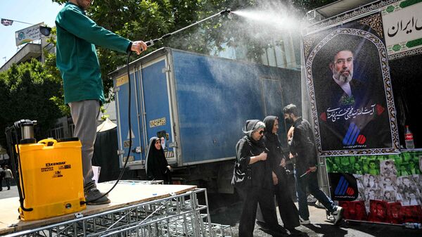 Latest news on July 5, 2026: People are sprayed with water to cool off during the heat while on their way to the Grand Mosalla in Tehran on July 5, 2026, for the funeral ceremonies of Iran's slain supreme leader Ayatollah Ali Khamenei. (Photo by Ozan KOSE / AFP) /