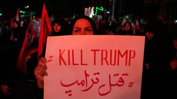 A pro-government demonstrator holds an anti-Trump placard in a gathering commemorating the late Iranian Supreme Leader Ayatollah Ali Khamenei at a square in Tehran, Saturday, July 11, 2026.