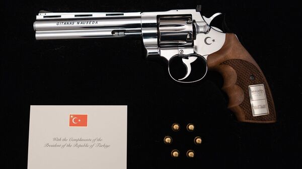 This handout photo taken and obtained on from the office of the Lithuanian President shows a revolver offered by Turkish President Recep Tayyip Erdogan to Lithuanian President Gitanas Nauseda with the president's name engraved, including live rounds, and displayed during a press presentation in Vilnius, Lithuania.