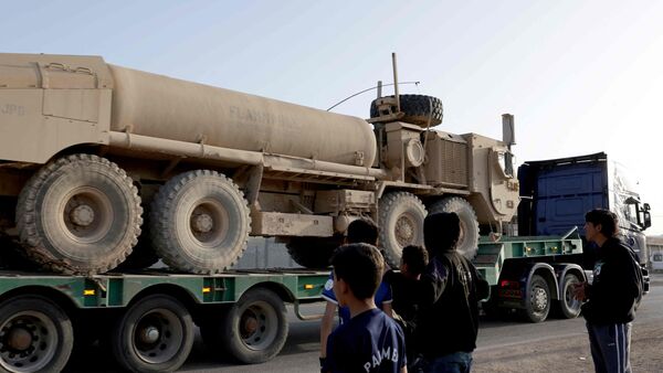 Latest news on July 15, 2026: Syrian youth look on as a convoy of US military equipment is transported near capital Damascus on April 16, 2026.