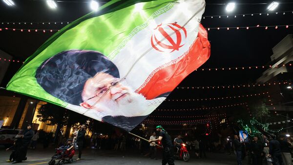 A man waves a flag near Imam Reza's shrine as mourners arrive for the funeral of slain Iranian leader Ali Khamenei and members of his family in Mashhad early on July 9, 2026. (Photo by ATTA KENARE / AFP)