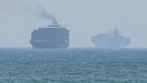 This frame grab taken from AFPTV video footage on July 12, 2026 shows cargo ships anchoring near the Strait of Hormuz off the eastern coast of the United Arab Emirates at Khor Fakkan. (Photo by AFPTV / AFP)