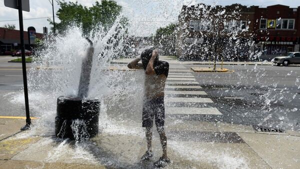 TOPSHOT - A person cools off with water from an open fire hydrant during a heat wave on the West Side of Chicago, Illinois