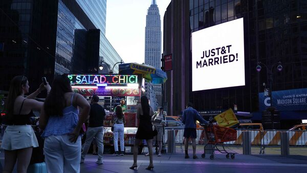 The Empire State Building is seen in the distance as people take photos of a giant screen showing the message 'JUST&T MARRIED' (T&T for Taylor and Travis) outside Madison Square Garden, the reported venue for the wedding celebrations of pop singer Taylor Swift and pro-athlete Travis Kelce, in New York City on July 3