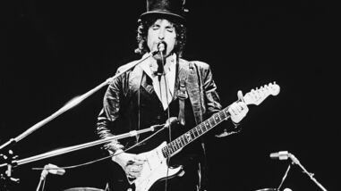 American singer and songwriter Bob Dylan sings and plays guitar on stage, wearing a top hat, during the Blackbushe Pop Festival, Hampshire, England, July 17, 1978. (Photo by Express Newspapers/Getty Images)